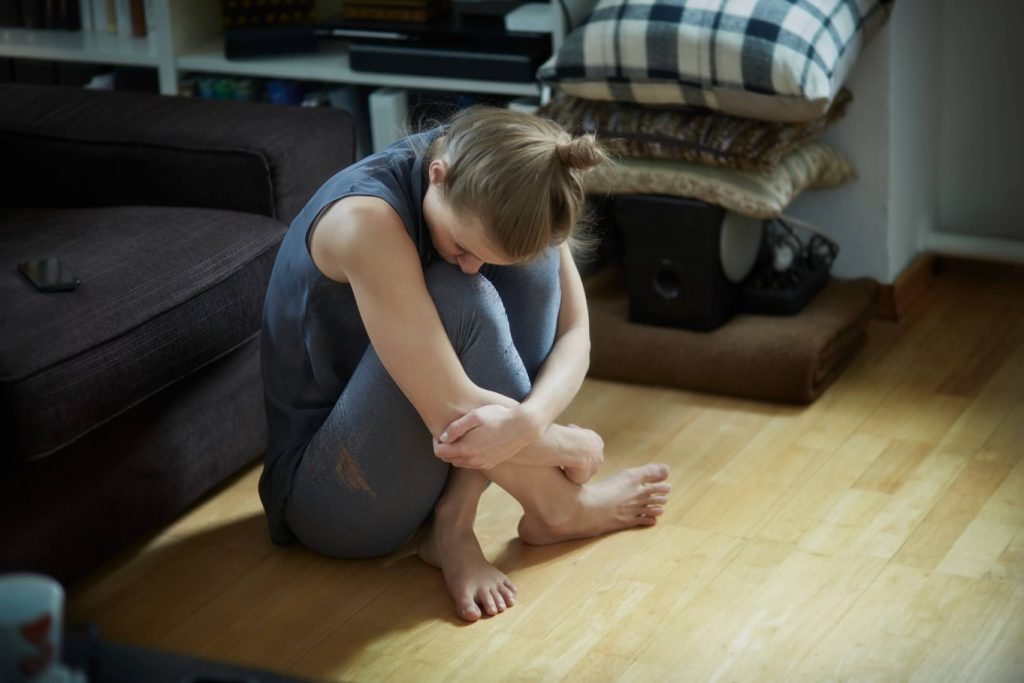Mulher sentada no chão nervosa simbolizando estresse pós traumático